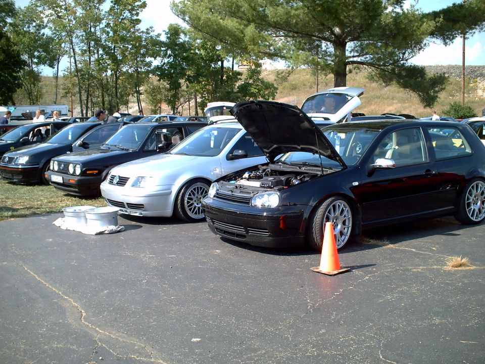 Black Volkswagen Golf GTI, hood open, parked in a line of cars
