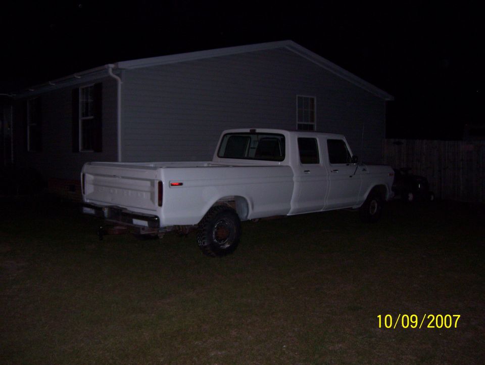 White 1978 Ford F-350 crew cab pickup truck, side view, parked in a yard at night