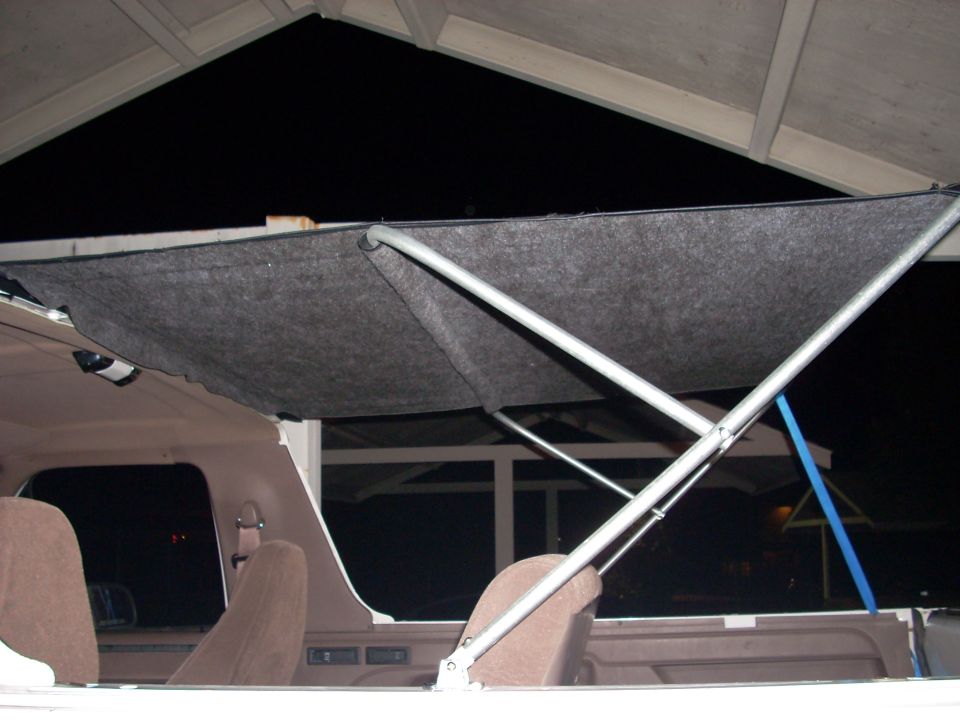 Gray fabric-covered soft top frame over the open cab of a truck with tan interior, seen at night