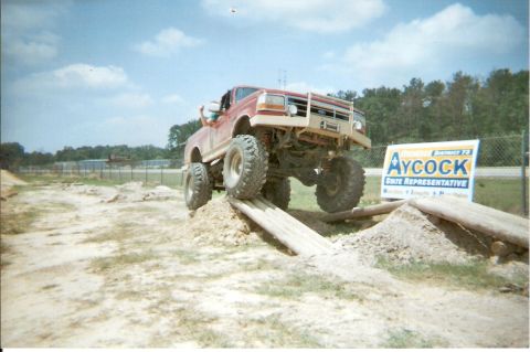 1995 Ford Bronco - This lifted Ford truck navigates an obstacle course, with a political sign in the background.