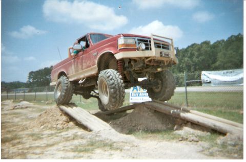 1995 Ford Bronco - This lifted red Ford truck navigates an offroad obstacle course.