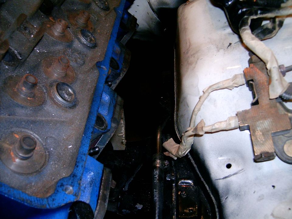 Engine block with blue gasket and wiring harness on white bulkhead