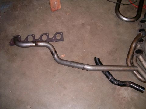 1978 Ford Mustang II - Exhaust manifold and pipe components laid out on a concrete floor.