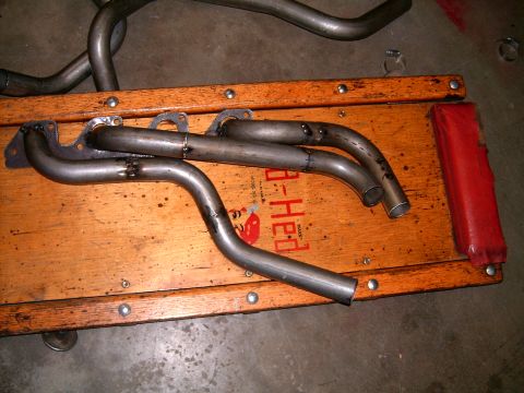 1978 Ford Mustang II - Custom exhaust headers are laid out on a wooden cart with a red handle.