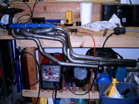 1978 Ford Mustang II - Custom exhaust headers and welding equipment are laid out on a wooden workbench.