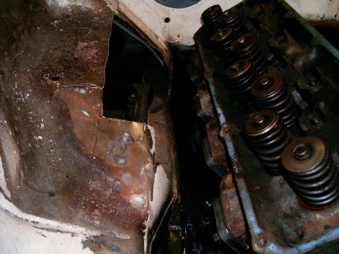 1978 Ford Mustang II - The engine's valve train is visible next to a heavily rusted and damaged section of the vehicle's inner fender.