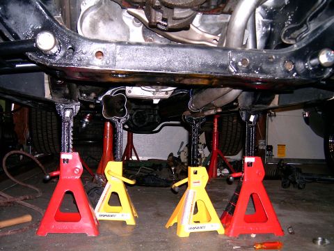 1978 Ford Mustang II - The car's undercarriage is supported by four jack stands, revealing the exhaust system and drivetrain components.