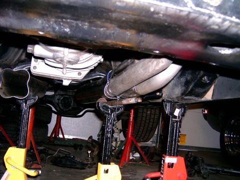 1978 Ford Mustang II - The underside of a vehicle is visible, supported by jack stands, with a focus on the exhaust system and drivetrain components.