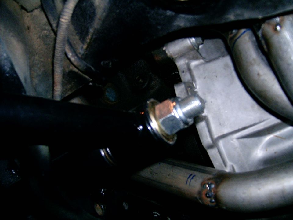 Engine block with exhaust headers and a black pipe. Close-up view