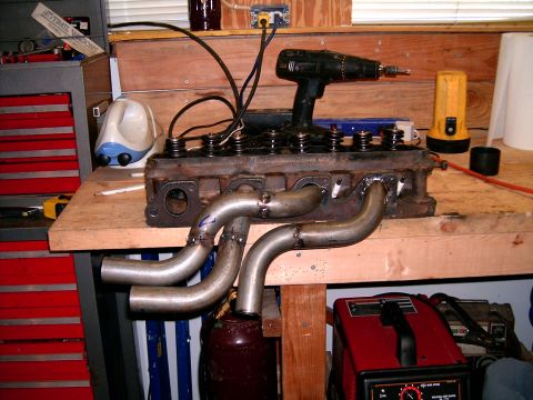 1978 Ford Mustang II - Custom exhaust headers are attached to an engine block, with a drill resting on top of the engine.