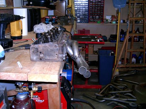 1978 Ford Mustang II - Custom exhaust headers fabricated and attached to an engine cylinder head in a workshop.