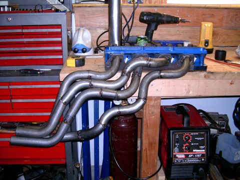 1978 Ford Mustang II - Custom exhaust headers are shown on a workbench with welding equipment and tools nearby.