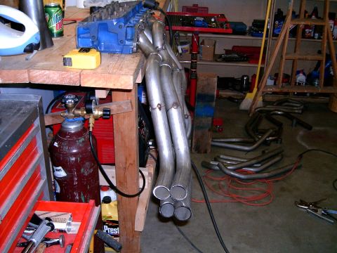 1978 Ford Mustang II - A collection of exhaust headers and automotive parts are visible in a workshop setting.