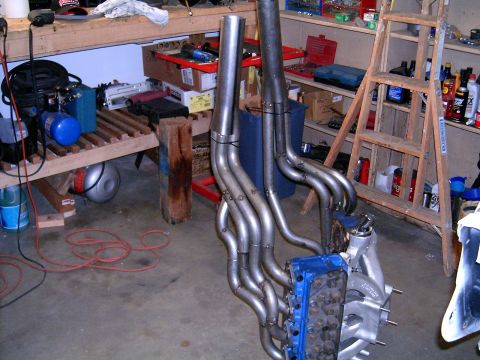 1978 Ford Mustang II - Custom exhaust headers are attached to an engine block in a cluttered garage setting.