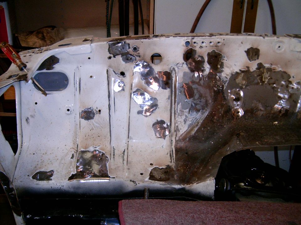 White car firewall with rust and holes, showing metal repairs