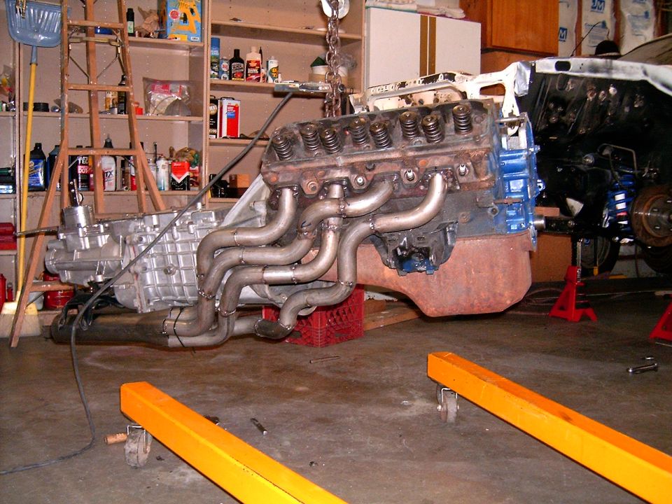 V8 engine with custom headers and transmission being hoisted