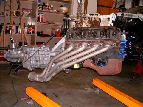 1978 Ford Mustang II - Engine and transmission assembly, custom headers, is suspended for work in a garage setting.