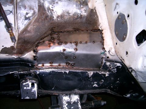 1978 Ford Mustang II - Close-up view of a section of a vehicle's frame undergoing repair with welded metal patches.
