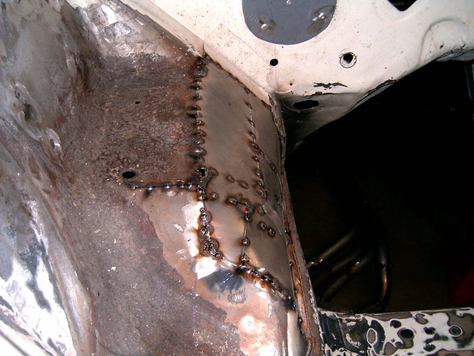 Welded metal repair in engine bay, showing patches and welds