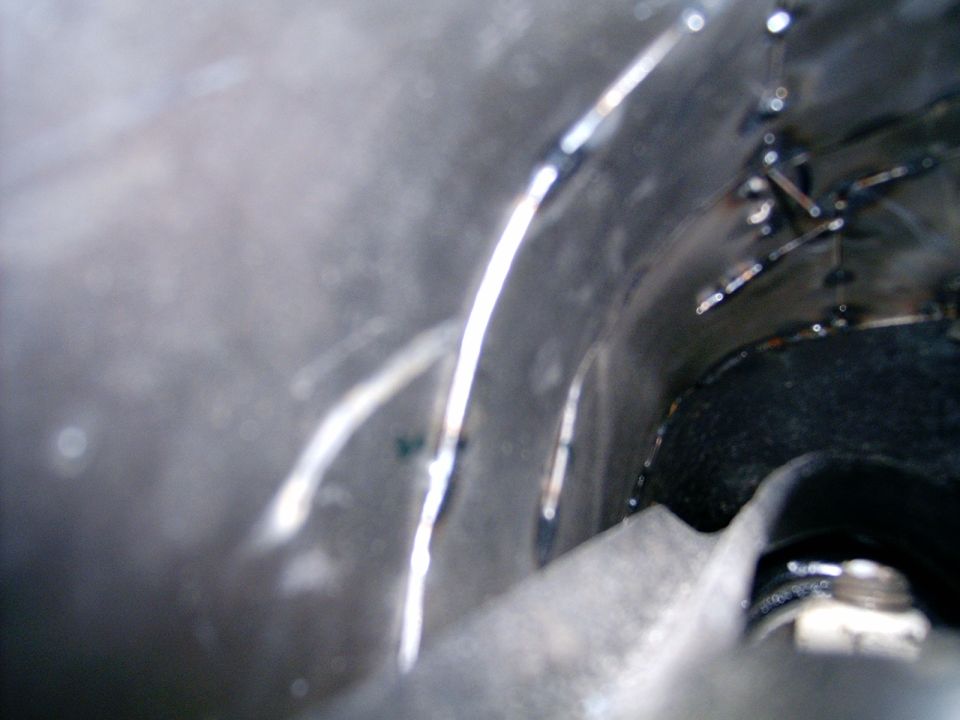 Welded metal interior of a vehicle part, showing rough seams and a bolt