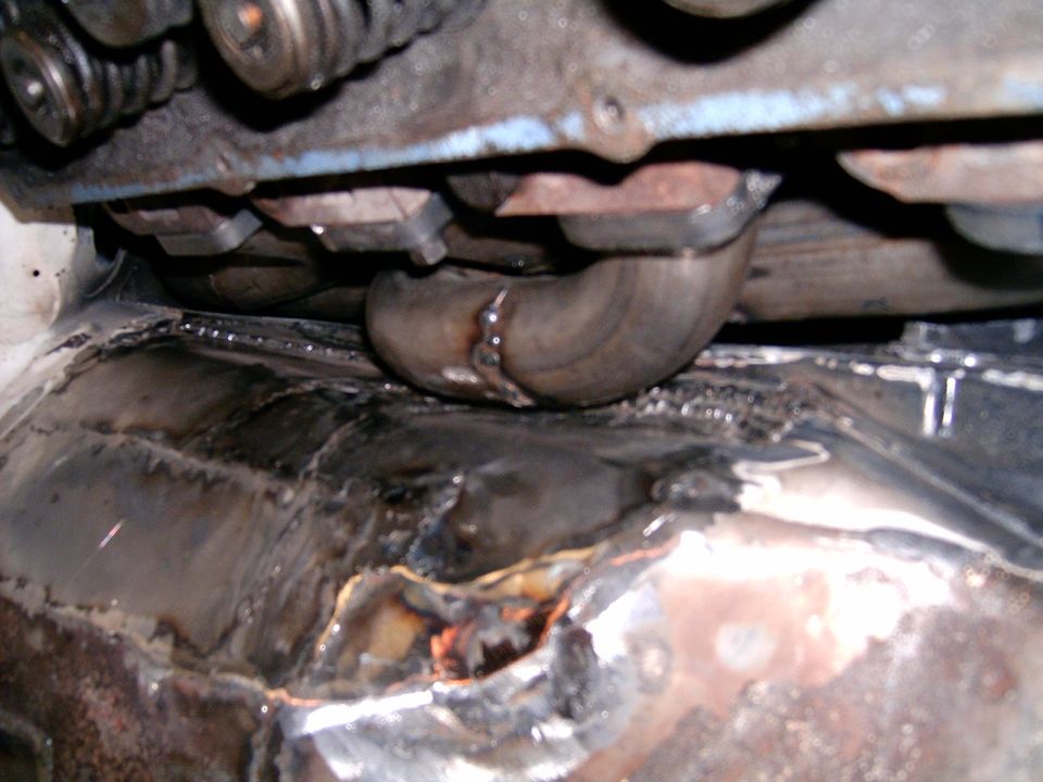 Exhaust pipe under engine components, showing welded floor pan