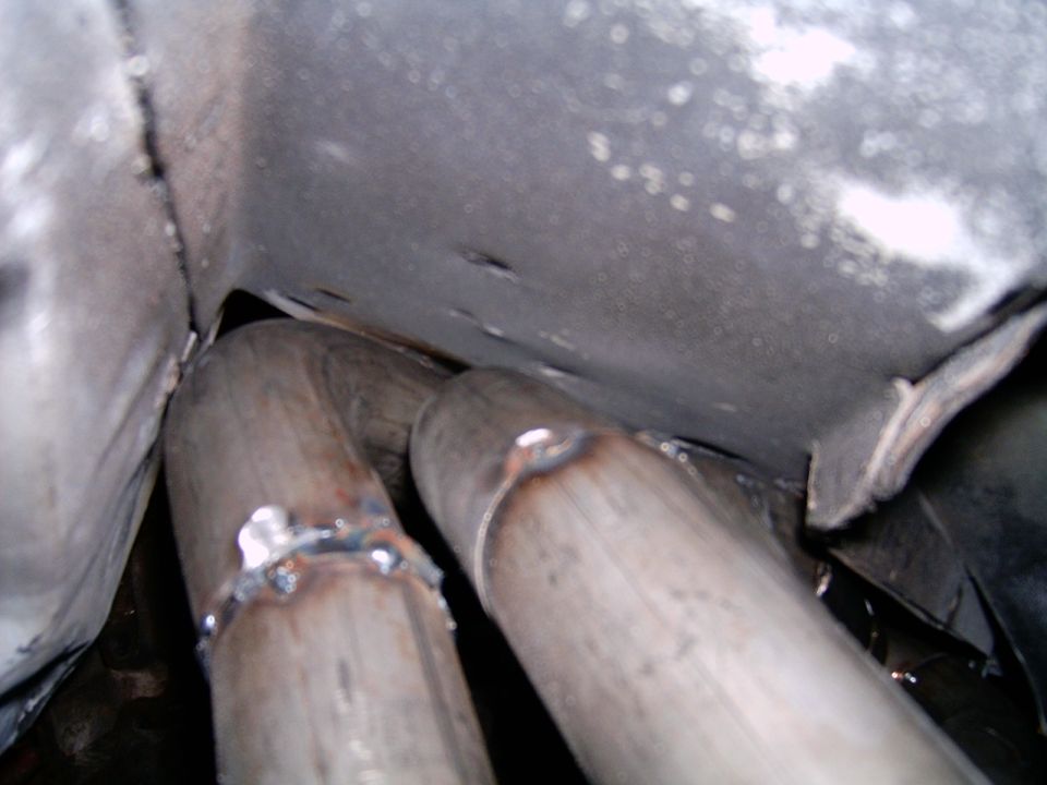 Dual welded exhaust pipes under a vehicle floor pan