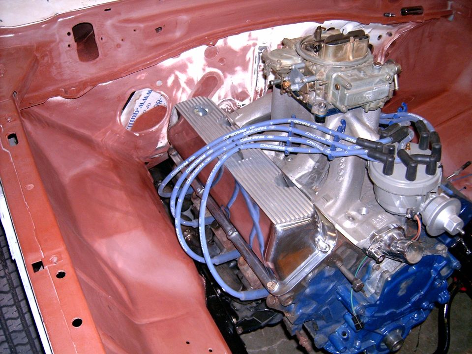Engine bay with V8 engine, chrome valve covers, and blue spark plug wires