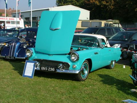 1988 Ford Sport - A classic turquoise and white convertible is displayed with its hood up, parked on a grassy field.
