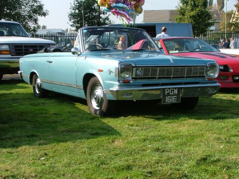 1988 Ford Sport - A light blue convertible is parked on grass next to a white truck and a red car.