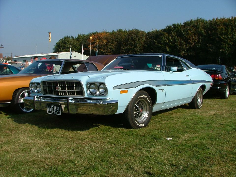 Light blue 1974 Ford Gran Torino Sport coupe with a grey stripe, parked on grass