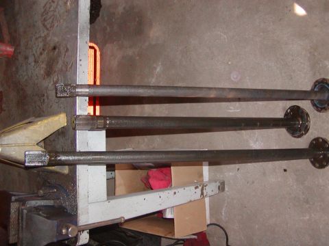 1991 Ford Bronco - Three axle shafts are laid out, one held in a vise, for comparison or repair.