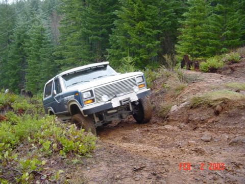 1985 Ford Bronco - Ford Bronco navigates a steep, wooded trail during an off-road excursion.