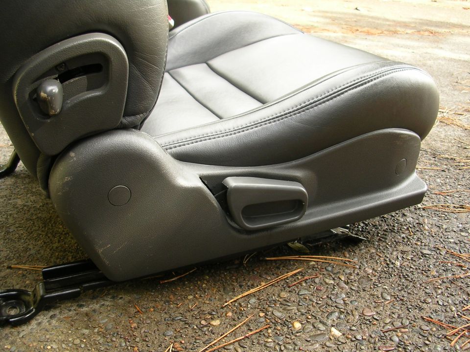 Black leather car seat with gray plastic trim and adjustment levers