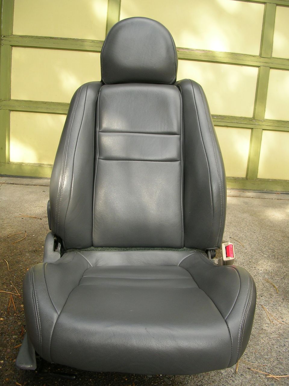 Black leather car seat with headrest and red seatbelt buckle