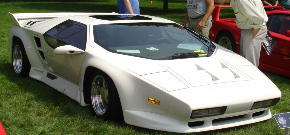 White Vector M12 sports car with a red car behind it