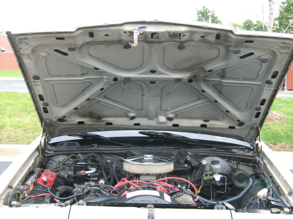 Open hood showing engine bay of a vehicle outdoors
