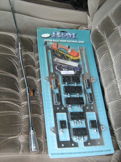 1988 Mercury Grand Marquis - A chrome antenna and a package of R&M custom billet spark plug wire looms are laid out on a textured gray fabric surface.
