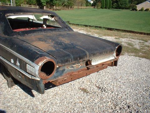 1963 Ford Galaxie - Rear view of a rusty 1963 Ford Galaxie, missing its taillights and bumper, with a white grille visible.
