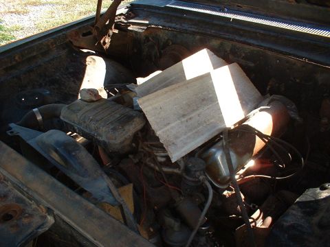 1963 Ford Galaxie - The engine bay of a car is shown, with parts obscured by wooden planks.