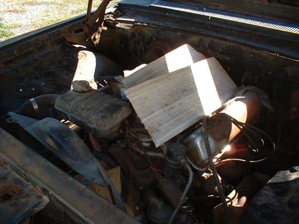 Dusty classic V8 engine bay with cardboard laid across the engine