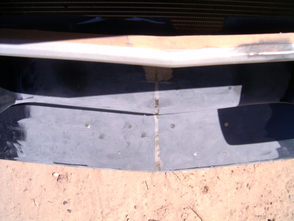 close-up of a gray car bumper with visible seam and screw holes