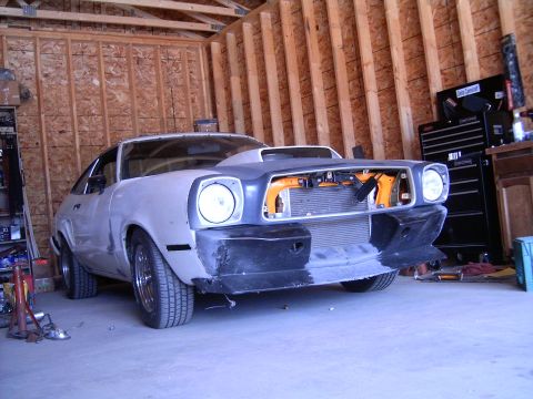 1978 Ford Mustang II - This 1975 Ford Mustang II is in a garage, appearing to be in the middle of a restoration project with its front end disassembled.