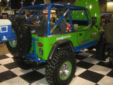 1990 Ford Bronco - bright green Jeep CJ-style vehicle with a blue roll cage, BFGoodrich tires and beadlock wheels parked on a checkered floor.