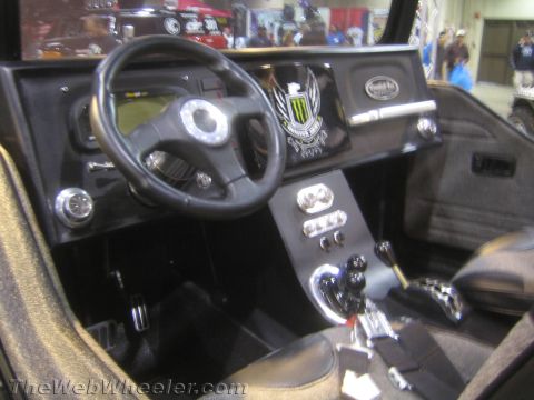 1990 Ford Bronco - Custom black vehicle interior with a leather steering wheel, Monster-energy dash emblem and polished chrome shift levers.