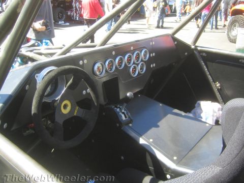 1990 Ford Bronco - bare-metal cockpit of an off-road race buggy shows a suede steering wheel and a black panel of round gauges.