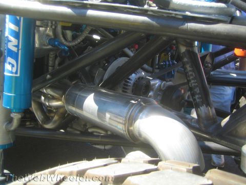 1990 Ford Bronco - close-up shows the polished exhaust, blue King shock and welded tube chassis under an off-road race vehicle.