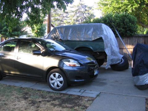 1989 Ford Bronco - A 1989 Ford Bronco is partially covered by a tarp in a driveway.