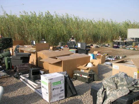 1996 Ford Bronco - An outdoor area filled with boxes and supplies, with tall reeds and a distant airplane under a clear sky.