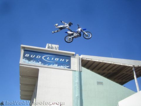 1990 Ford Bronco - freestyle motocross rider lays out flat over a blue dirt bike high above a Bud Light stadium sign.