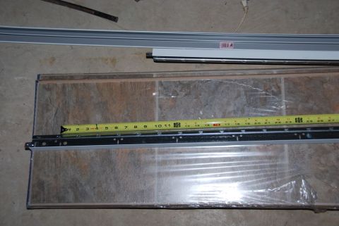 1996 Ford Bronco - A measuring tape is placed over a piece of flooring and a metal track, likely for installation.